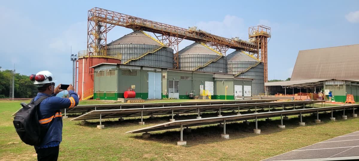 Usina em solo de grande porte ao lado de silos de armazenagem de grãos